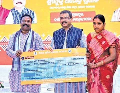 Pradhan handing over maternity benefit of Rs 10,000 to a worker