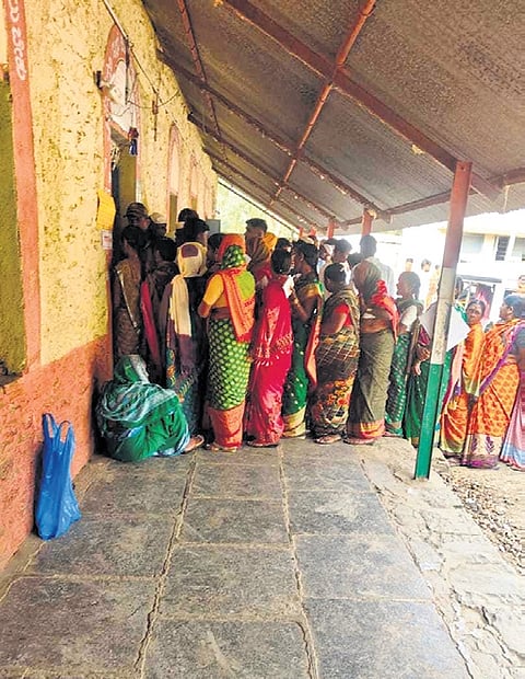 Voters wait outside a polling booth at a border village in Umadi Jatt taluk in Maharashtra on Monday afternoon