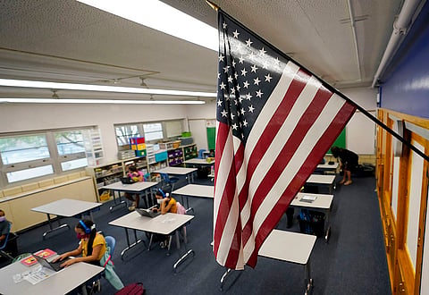 An American flag hangs in a classroom as students work on laptops in Newlon Elementary School.