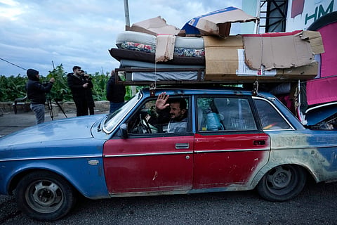 A man who is returning to his village waves as he carries his belongings on his car after the ceasefire between Hezbollah and Israel began early morning, in Tyre, south Lebanon.