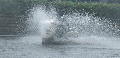 A motorist rides through waterlogged road in Pudhucherry on Saturday