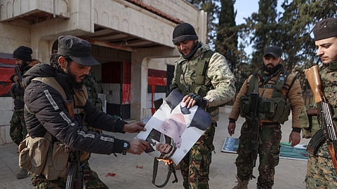 Fighters set alight a picture of Syrian President Bashar al-Assad in front of a building that was seized by jihadists in the area of Zarbah on November 29, 2024, as Hayat Tahrir al-Sham (HTS) jihadists and allied groups continue their offensive in Syria's northern Aleppo province against government forces.