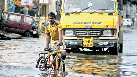 A boy pushing his bicycle through an inundated Teachers Colony
Main Road in Kolathur, Chennai during the floods in 2015.