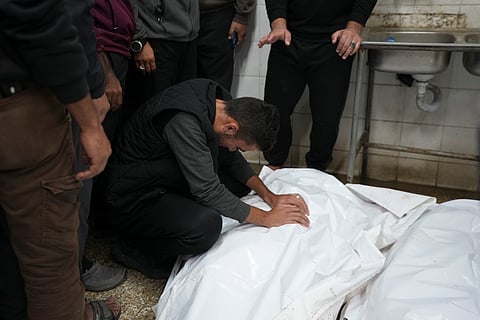 A Palestinian man mourns over bodies of a victim following Israeli bombardments, at the morgue of Al-Aqsa Martyrs hospital in Deir al-Balah, Gaza Strip, Sunday, Dec. 8, 2024.