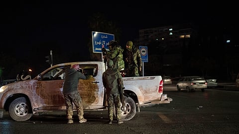 Syrian fighters stand on a street at the central square in Damascus, Syria.