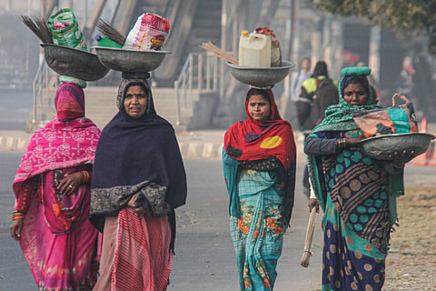 Women walk on a road during a cold winter morning, in Gurugram on Saturday.