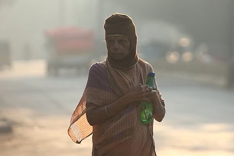 A woman covers herself with a winter wear to protect her from cold weather at Vidhya Nagar in Hyderabad on Tuesday.