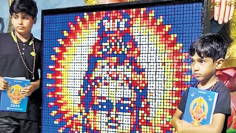 Abhinav Krishnan, 10, and Advaith Krishnan, 6, stand beside their portrait of Lord Ayyappa made using Rubik’s Cube, at Sree Dharma Sastha auditorium in Sabarimala