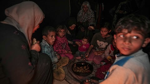 Amani Abu Zarada, fourth from left, feeds one of her children in a camp in Khan Younis, Gaza Strip.
