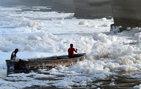 Workers spray chemicals to dissolve toxic foam in the polluted Yamuna river at Kalindi Kunj during 'Chhath'' festival, in New Delhi, 2024.