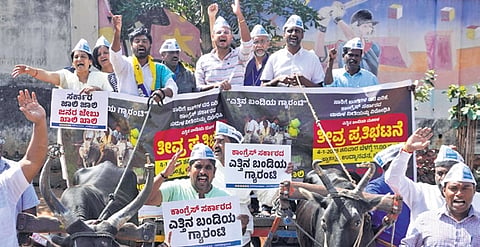 AAP members shout slogans as they take out a bullock cart during a protest against the bus fare hike, in Bengaluru on Saturday