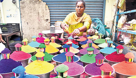 a woman who sells colour Kolam powder setting up stocks on display for festival sale