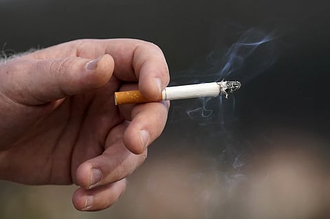 A man holds a lit cigarette while smoking in San Francisco, Wednesday, Dec. 2, 2020.