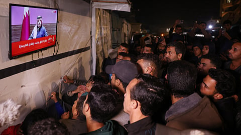 People watch the live television broadcast of a press conference being addressed by Qatar’s Prime Minister Sheikh Mohammed bin Abdulrahman bin Jassim Al-Thani, along a street in Khan Yunis in the southern Gaza Strip on January 15, 2025, amid the ongoing war in the Palestinian territory between Israel and Hamas.
