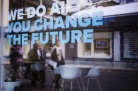 People reflected in a window with a slogan about AI at a representation of a company ahead of the World Economy Forum in Davos, Switzerland, Sunday, Jan 19, 2025