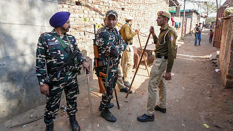 Police and security personnel stand guard at a resettlement colony of Pakistani Hindu refugees during the Delhi Assembly elections, at a resettlement colony at Majnu Ka Tilla area, in New Delhi.