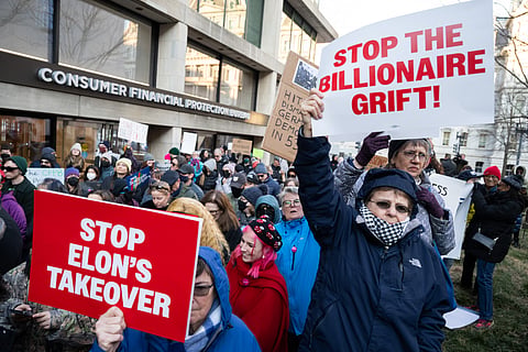 Demonstrators hold signs as they protest against US President Donald Trump and DOGE Elon Musk's anticipated plan to close the Consumer Financial Protection Bureau in front of the CFPB headquarters in Washington, DC, February 10, 2025.