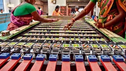A worker carefully stacks freshly dipped matchsticks for drying at a factory in Kovilpatti, Tamil Nadu.
