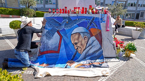 Mexican painter Roberto Marquez places a painting of Pope Francis he made outside the Agostino Gemelli hospital in Rome, Wednesday