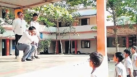ZP school headmaster Ramana performs sit-ups in front of students