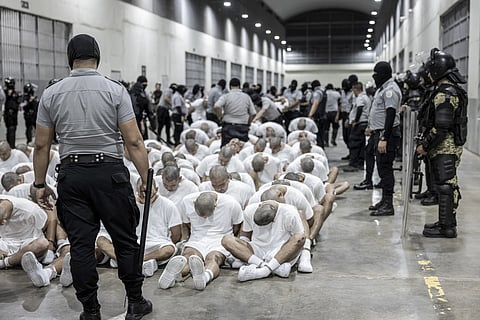 In this photo provided by El Salvador's presidential press office, a prison guard transfers deportees from the US alleged to be Venezuelan gang members, to the Terrorism Confinement Center in Tecoluca, El Salvador