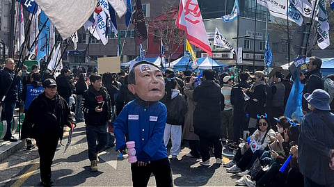 A man wearing a mask of President Yoon Suk Yeol celebrates along with others after Yoon was removed from office, near royal palace in downtown Seoul, South Korea, Friday, April 4, 2025.