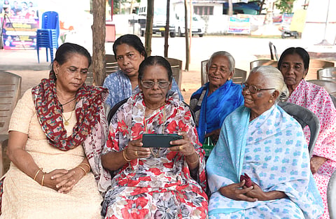 Munambam protesters eagerly watch the live debate on the Waqf Amendment Bill on mobile phone on Wednesday on the premises of Our Lady of Velankanni Church, Kadappuram