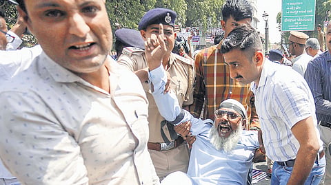 Policemen detain a protester against the Waqf bill in Ahmedabad on Friday