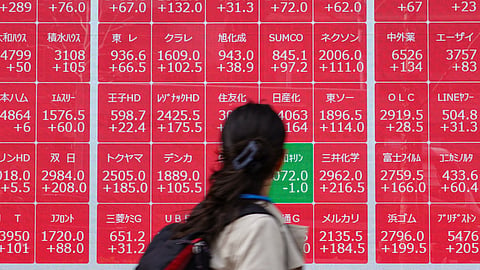 A woman looks at an electronic board showing the Nikkei 225 index on the Tokyo Stock Exchange in Tokyo on April 8, 2025.