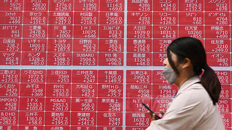 A person walks past an electronic stock board at a securities firm in Tokyo Thursday, April 10, 2025.