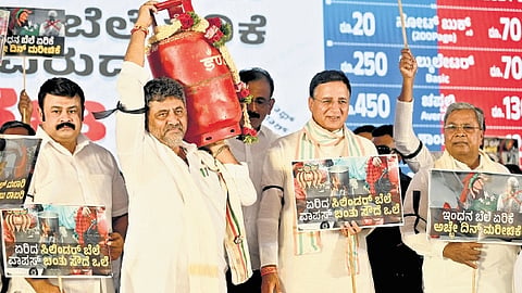 CM Siddaramaiah, DCM DK Shivakumar, and AICC general secretary Randeep Singh Surjewala hold placards, during a protest in Bengaluru on Thursday