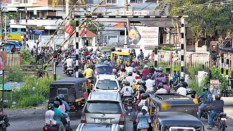 Vehicles jostle to cross over as the railway gate at Kureekad opens after a train passes on Sunday evening