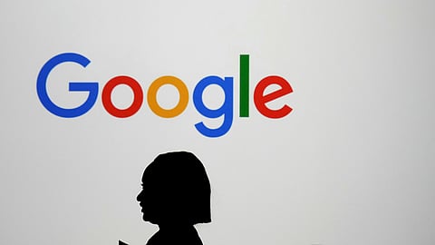 A woman walks by a giant screen with a logo at an event at the Paris Google Lab on the sidelines of the AI Action Summit in Paris, Sunday, Feb. 9, 2025.