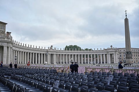 Two men stand near chairs during the preparations in St. Peter's Square ahead of the arrival of the body of Pope Francis, who will lie in state at St. Peter's Basilica for three days, at the Vatican, Wednesday, April 23, 2025.
