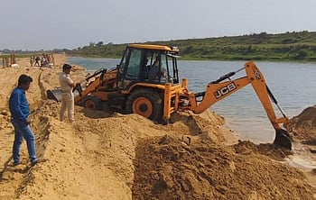 Mining officials demolishing the embankment on Devi river