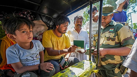 A security personnel checks the passports of Pakistani nationals as they arrive at the Attari-Wagah border to move to their country, near Amritsar
