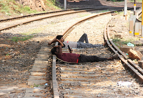 Amidst rising summer heat, workers are seen resting along railway tracks under a tree's shade near the port area in Visakhaptanam.