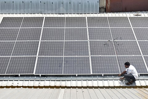 A worker installing solar panels on the roof of a building in Coimbatore. Image used for representational purposes only.