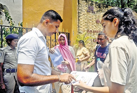 Officials check the students before allowing them inside the exam centre at Guru Nanak College in Chennai on Sunday