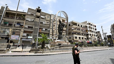 An armed man walks at Syouf Square in the mostly Druze and Christian Damascus suburb of Jaramana on April 30, 2025.