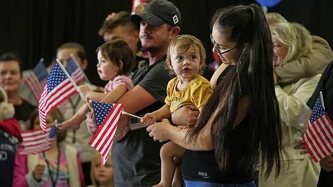 Afrikaner refugees from South Africa holding American flags, arrive, Monday, May 12, 2025, at Dulles International Airport, Dulles, Va.