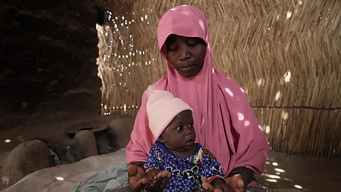 Yagana Bulama, a 40-year-old woman, plays with her surviving infant under the dappled light of a thatched shelter in Dikwa, northeastern Nigeria, Tuesday, April 29, 2025.