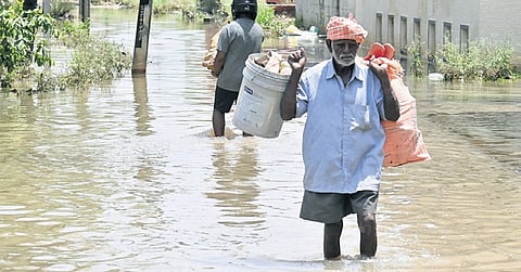 An elderly resident wades through a flooded road in Sai Layout in Bengaluru on Sunday, following torrential rain the previous day