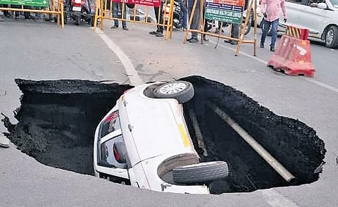 On Saturday evening, a car carrying a family of four and a driver got stuck in a sinkhole that suddenly opened up beneath it while waiting at the Thiruvanmiyur junction signal.
