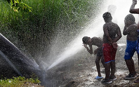 Boys enjoying drinking water main pipeline leakage under the Mysuru Road service area on Friday