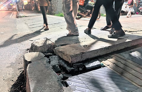 Pedestrians walk past an uneven footpath at MG Road