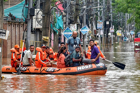 National Disaster Response Force (NDRF) personnel and others move through a waterlogged road aboard a rescue boat to distribute relief material to affected people at an area inundated with rainwater after heavy rainfall, in Guwahati, Assam, Saturday, May 31, 2025.