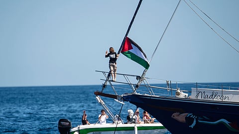 Climate activist Greta Thunberg stands near a Palestinian flag after boarding the Madleen boat and before setting sail for Gaza along with activists of the Freedom Flotilla Coalition, departing from the Sicilian port of Catania, Italy, Sunday, June 1, 2025
