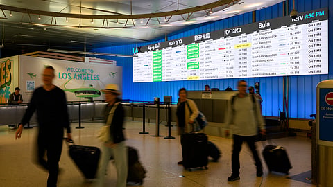 Travelers push their luggage through the international arrivals area at the Los Angeles International Airport in Los Angeles, Saturday, June 8, 2025.