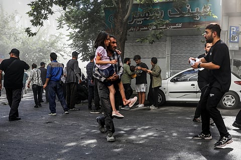 A man carries a wounded girl after an explosion in downtown Tehran amid Israel's three-day campaign of strikes against Iran, Sunday, June 15, 2025.